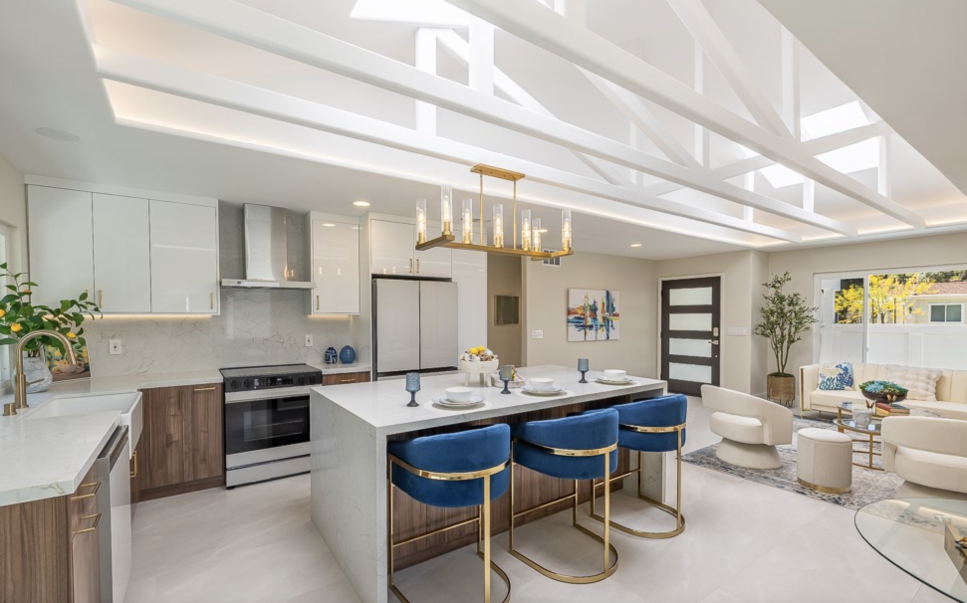 Open-concept kitchen with walnut cabinetry, blue velvet counter stools, and vaulted skylight ceiling