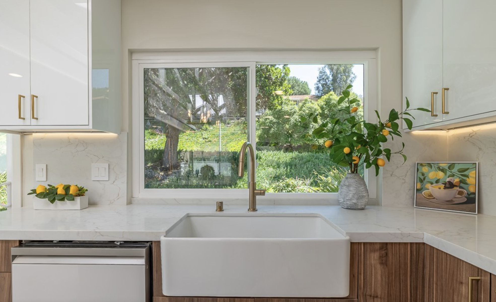 Kitchen window with farmhouse sink, brass faucet, marble counters, and garden view